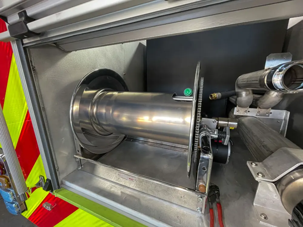 Exterior view of small fire truck showing cab, body compartments, and wheel/tire area.